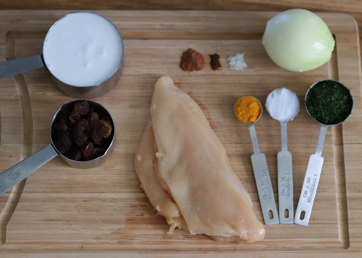 all the ingredients for coconut chicken curry on a wooden board