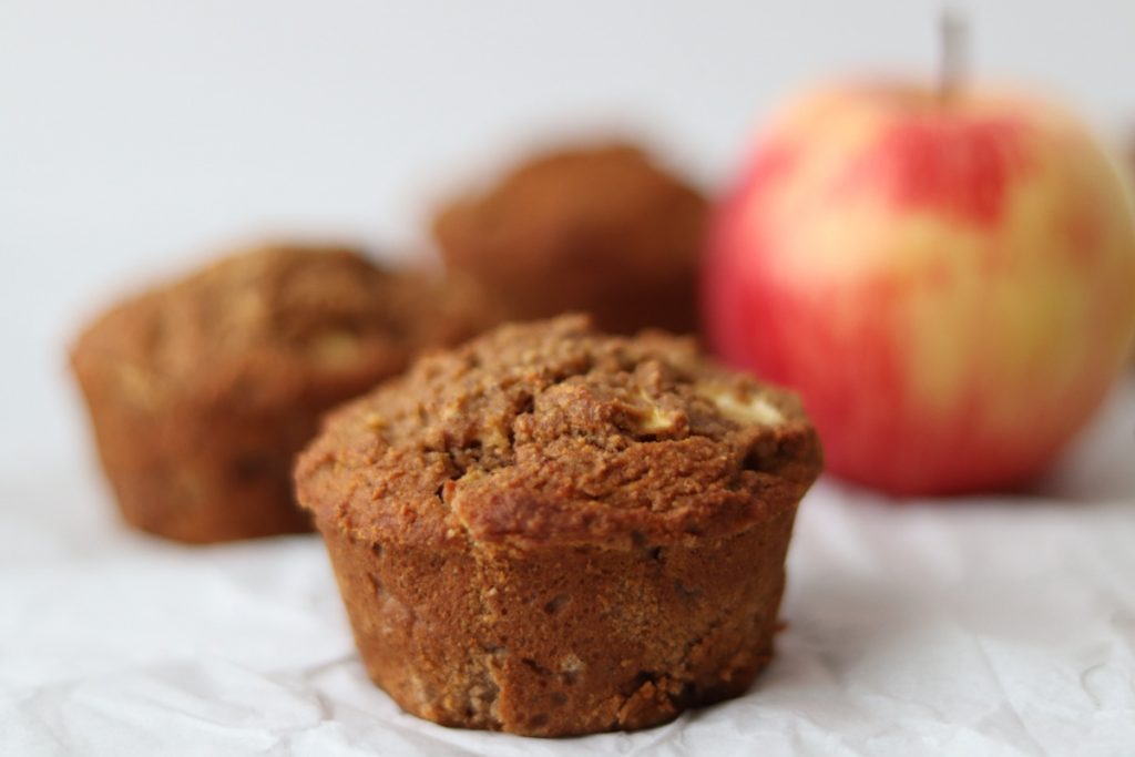 3 muffins à la pomme et une pomme sur un papier blanc