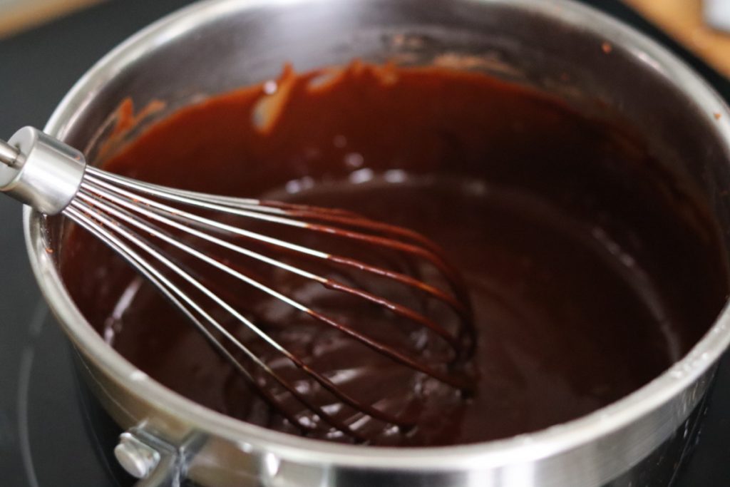 carob sauce in a sauce pan and a whisk