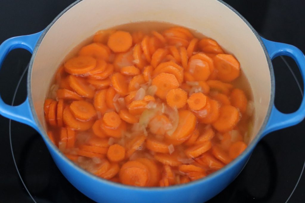 carottes et oignon en train de cuire dans l'eau dans une cocotte 