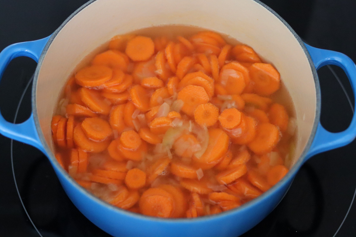 onion, carrots and water in a Dutch oven on the stove top to make a carrot coconut soup