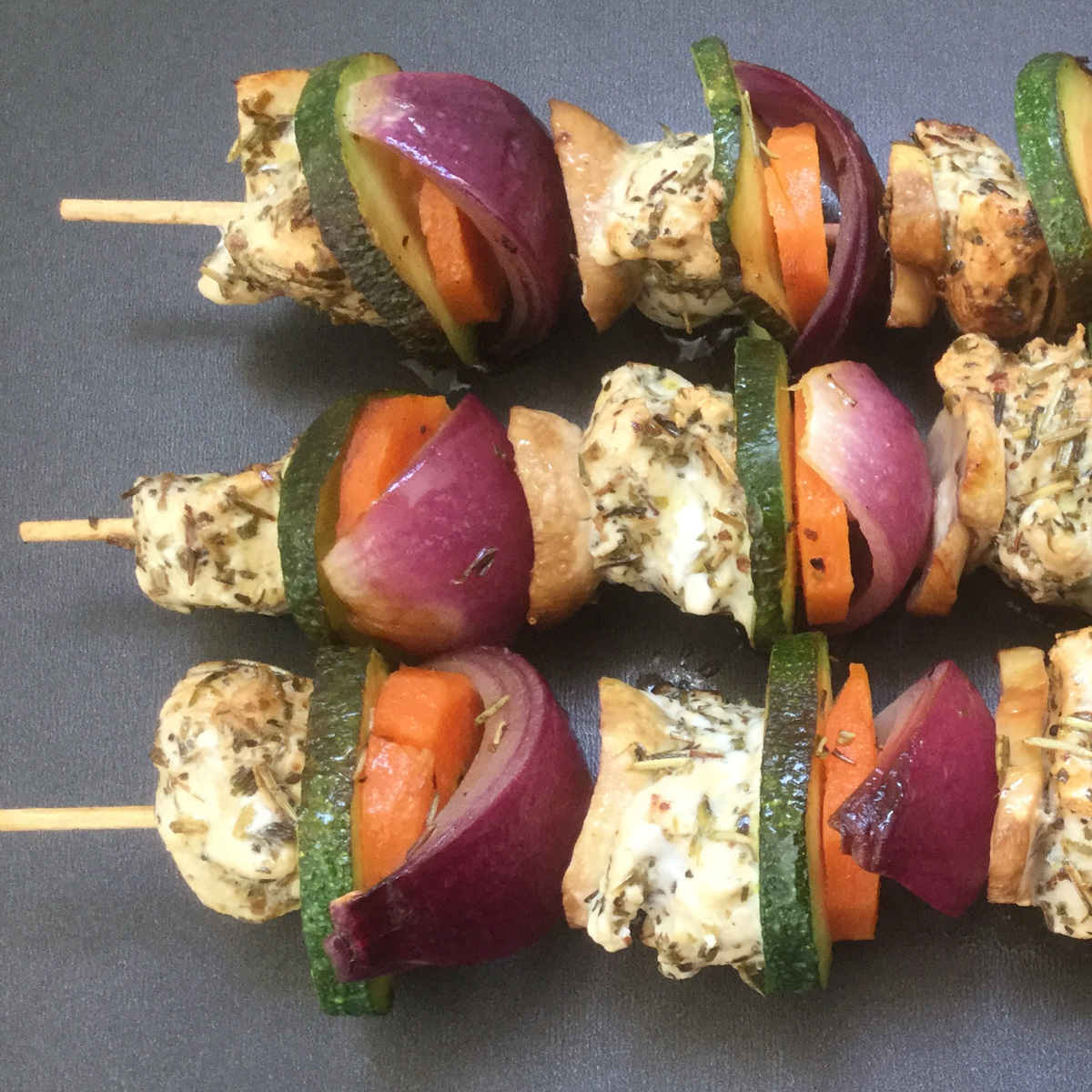 3 chicken kabobs on a black tray