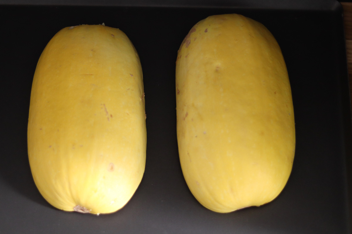 2 spaghetti squash halves cut side down on a baking tray