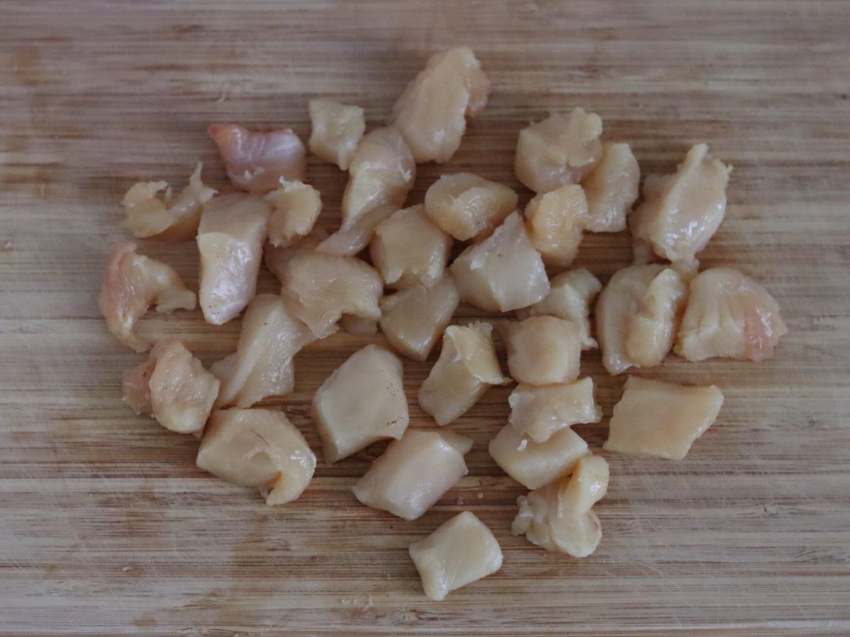 chicken breast cut into cubes on a wooden board