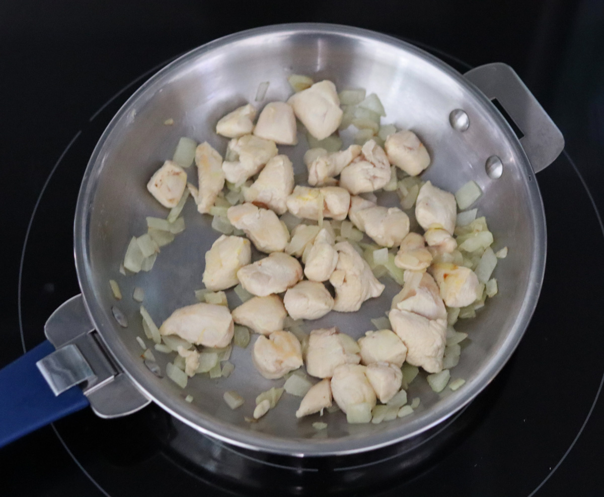 onion and chicken breast cut in cubes cooking togehter in a skillet