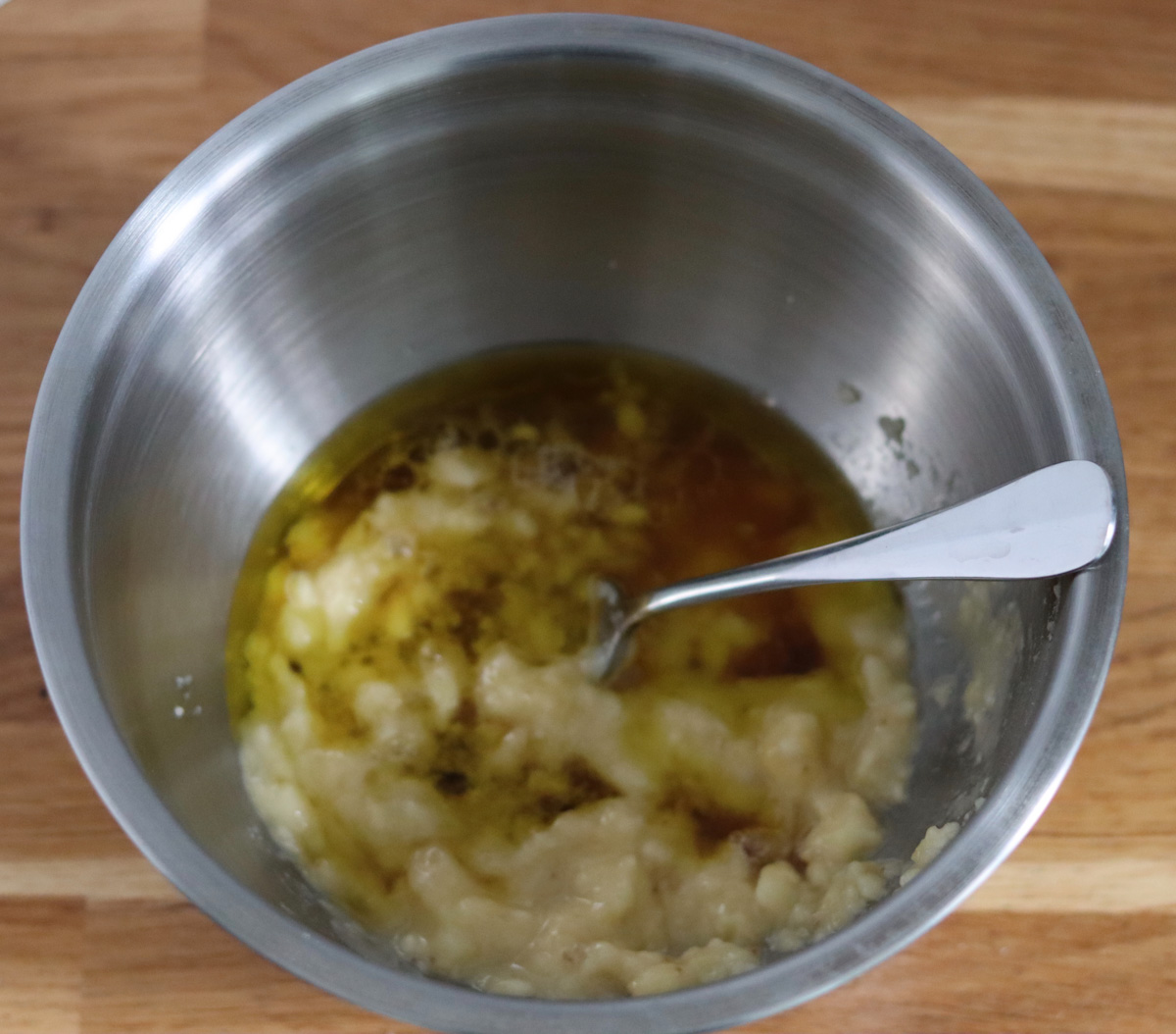all the wet ingredients mixed in a bowl with the mashed bananas