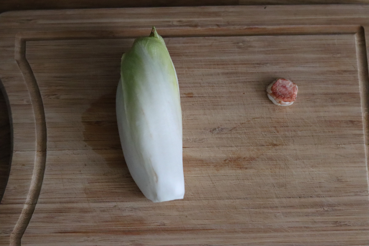 an endive with the tip removed on a cutting board