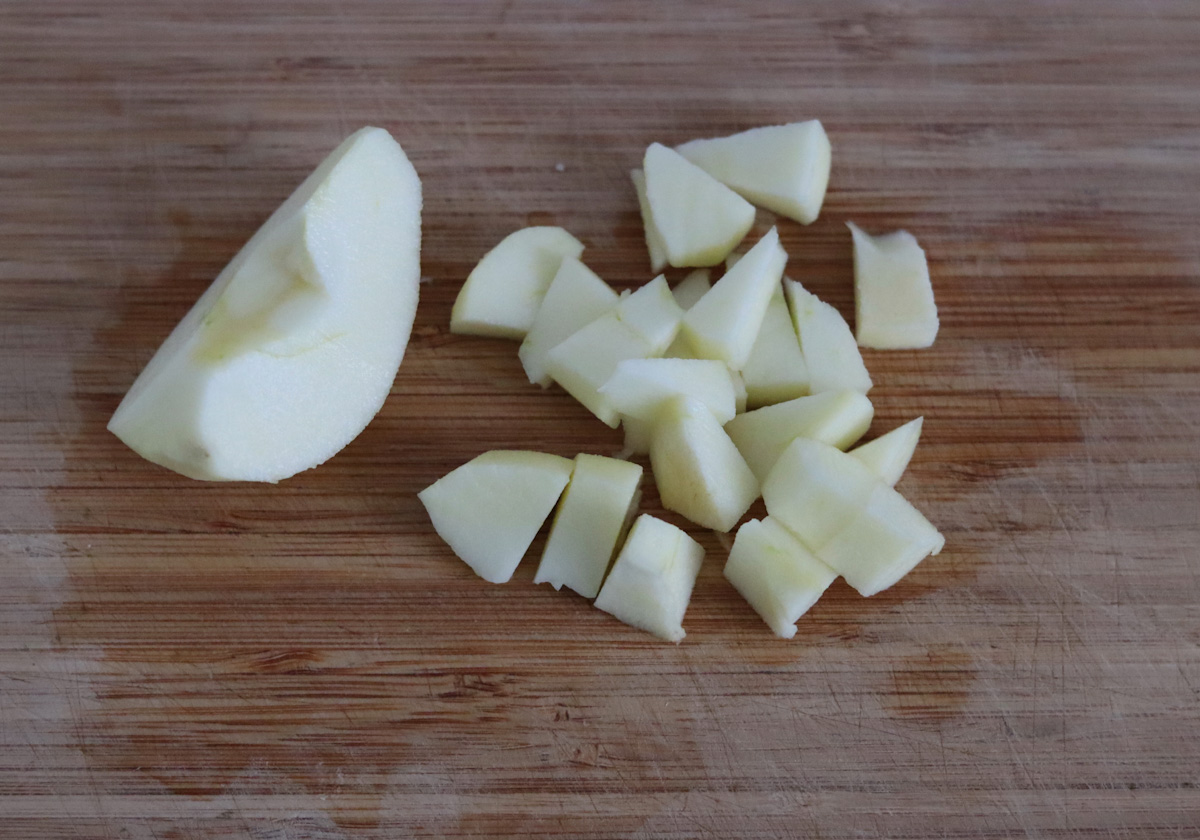 an apple peeled and cut in bite sized pieces on a cutting board