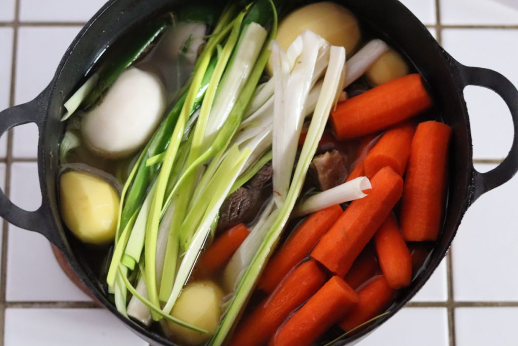 All the ingredients for the French beef stew pot au feu in a large Dutch oven