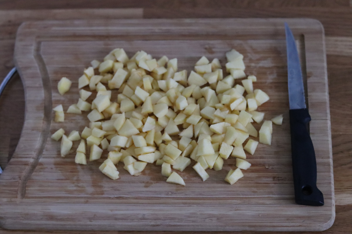 pommes pelées et coupées en morceaux sur une planche en bois et un couteau de cuisine