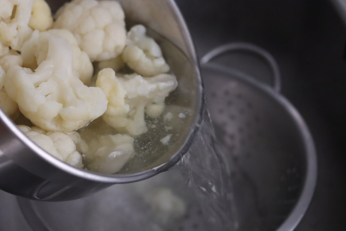 cauliflower being drained from a sauce pan