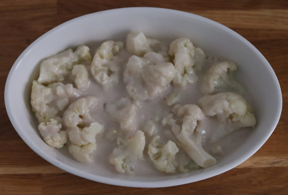 cauliflower florets topped with bechamel sauce in a baking dish