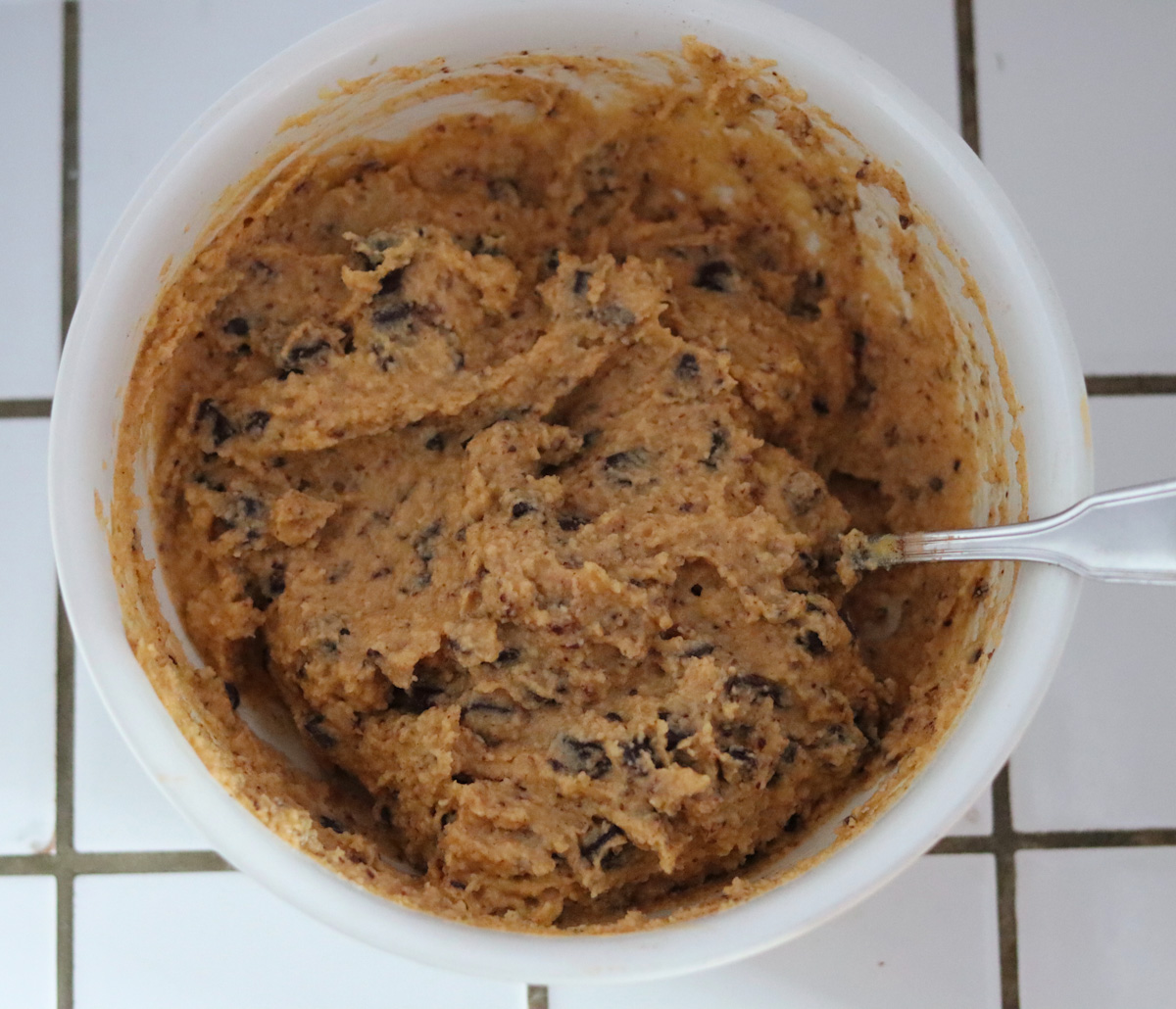 chocolate chip pumpkin bread batter in a large white bowl with a spoon