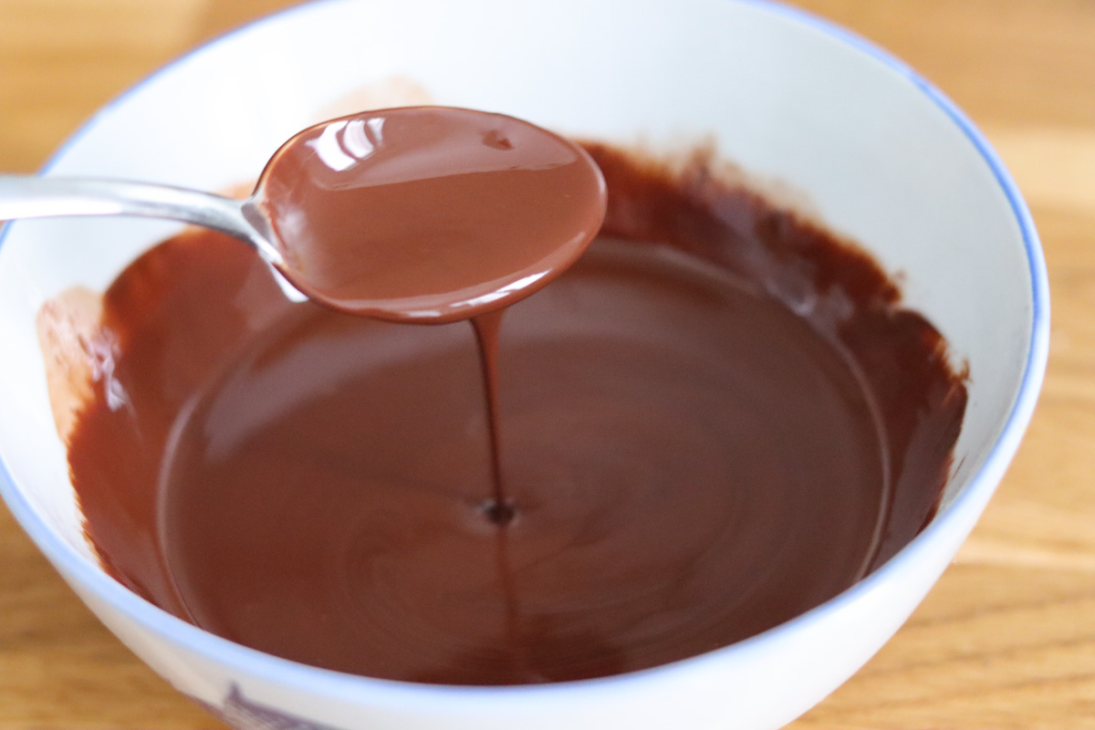 chocolat et huile de coco fondus dans un bol et une cuillère qui fait couler du chocolat pour voir la consistence
