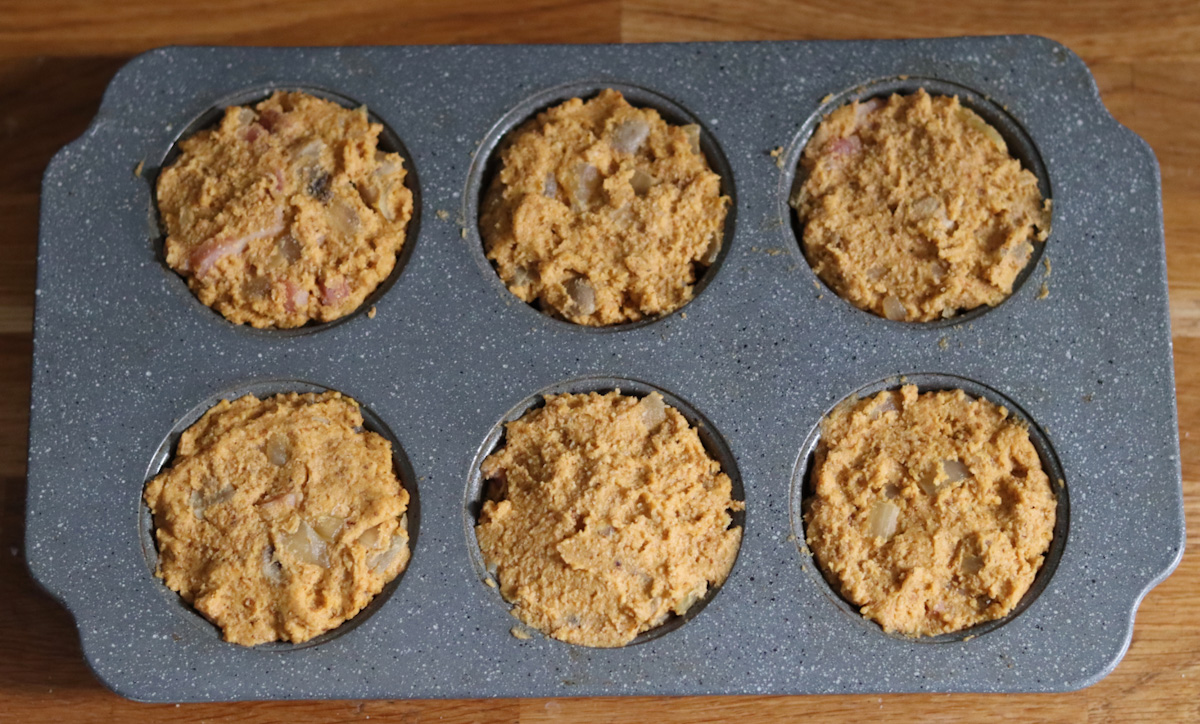 sweet potato and bacon muffin batter in a muffin pan
