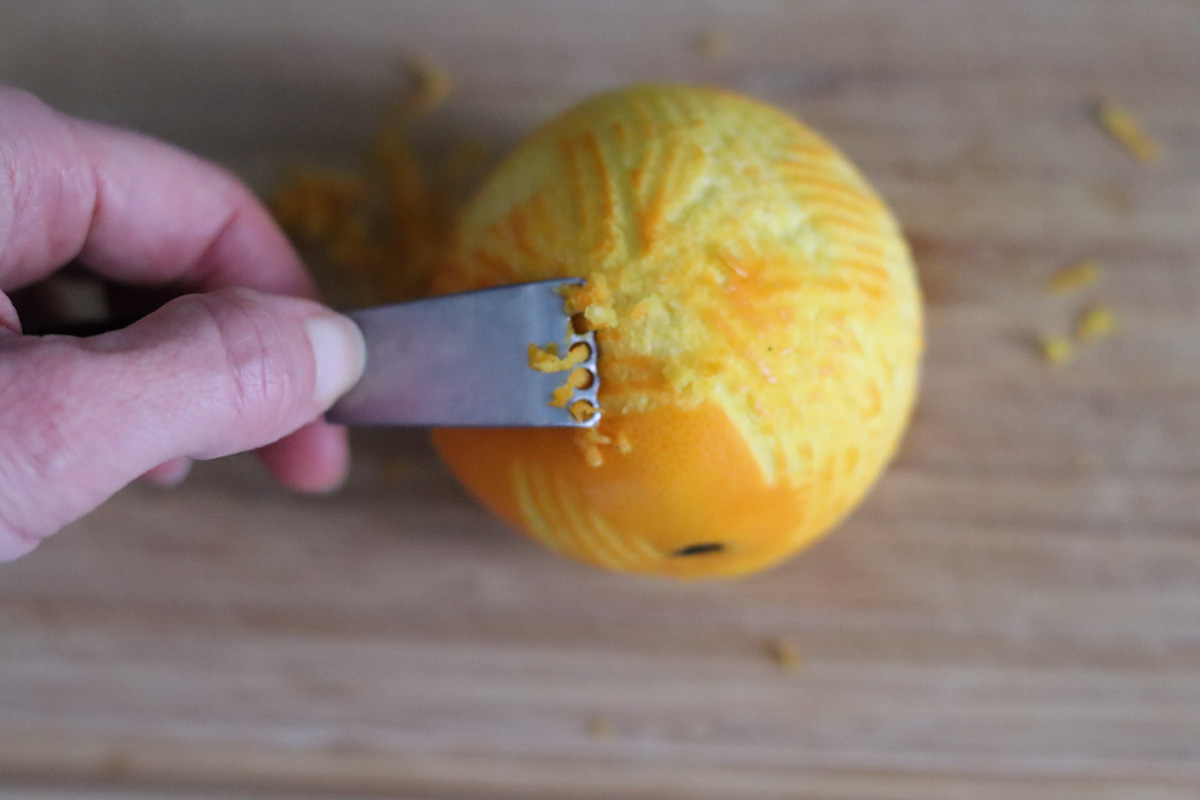 une orange dont on est en train de prélever le zeste