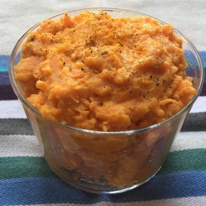 Mashed sweet potatoes in a glass jar on a table cloth