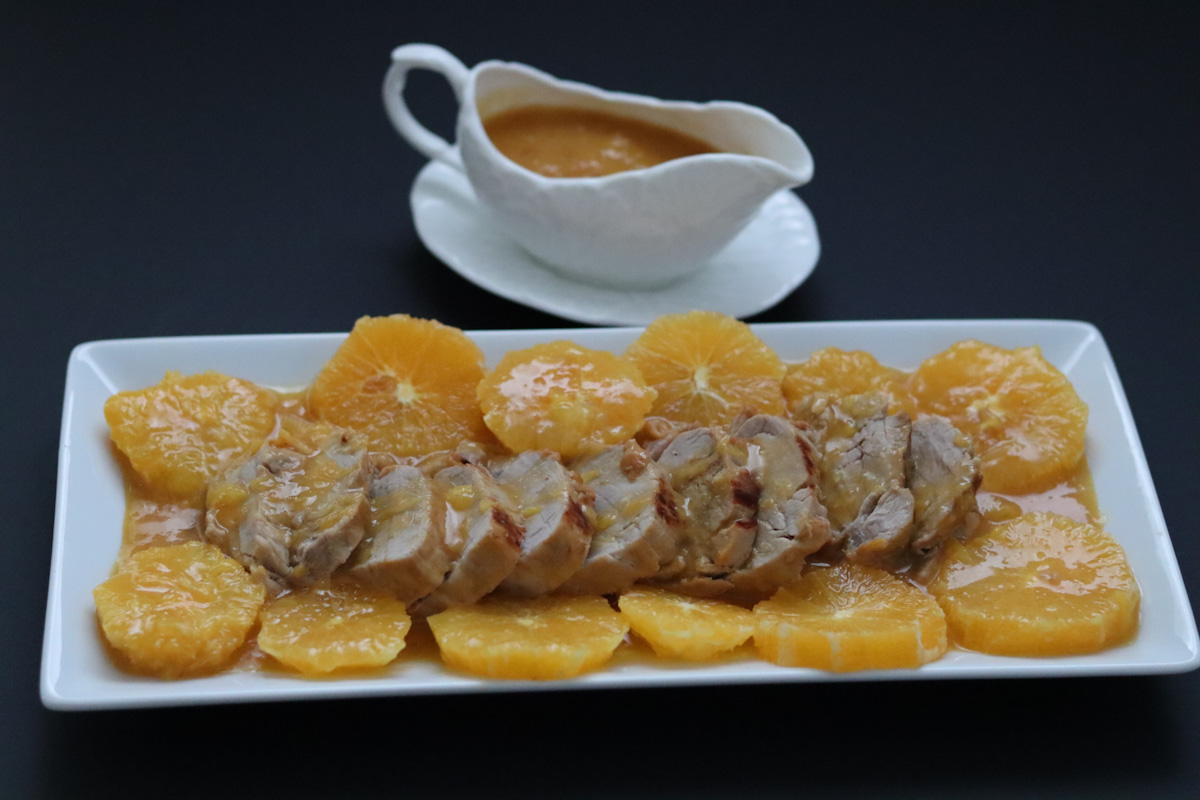 pork tenderloin on a serving plate with orange slices for garnish and 