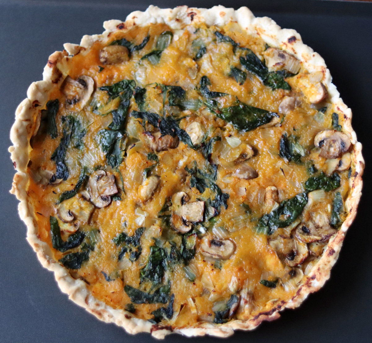 a pumpkin and spinach quiche on a black tray