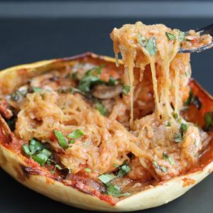 a fork taking some stuffed spaghetti squash with chopped basil on top