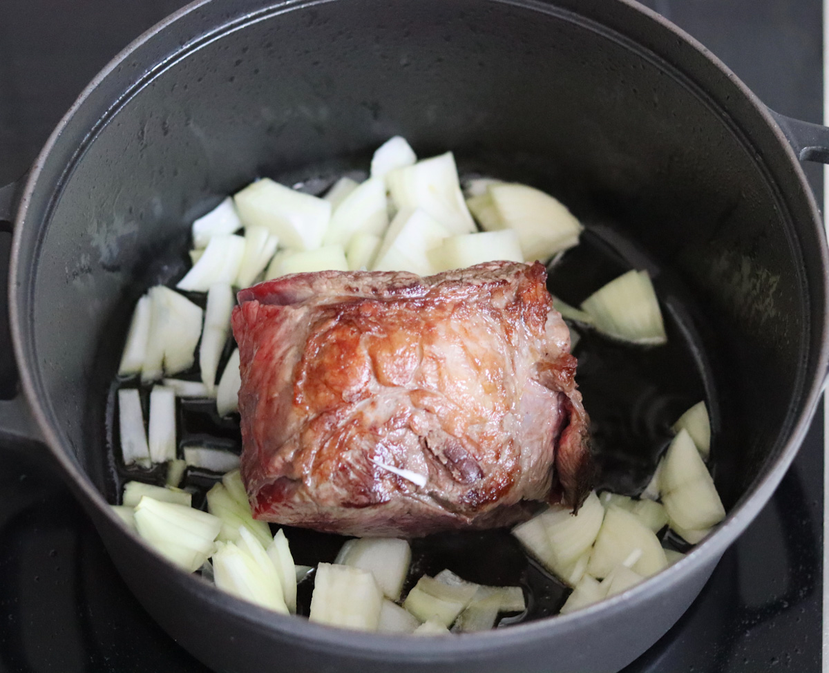 beef stew meat and diced onion cooking in olive oil in a large black Dutch oven