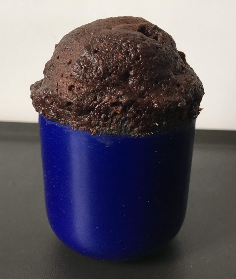 un mug cake chocolat qui a bien levé dans un mini mug bleu