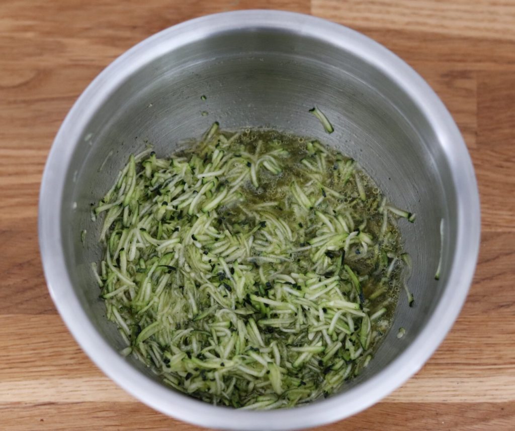 wet ingredients and grated zucchini for the carob zucchini bread combined in a bowl
