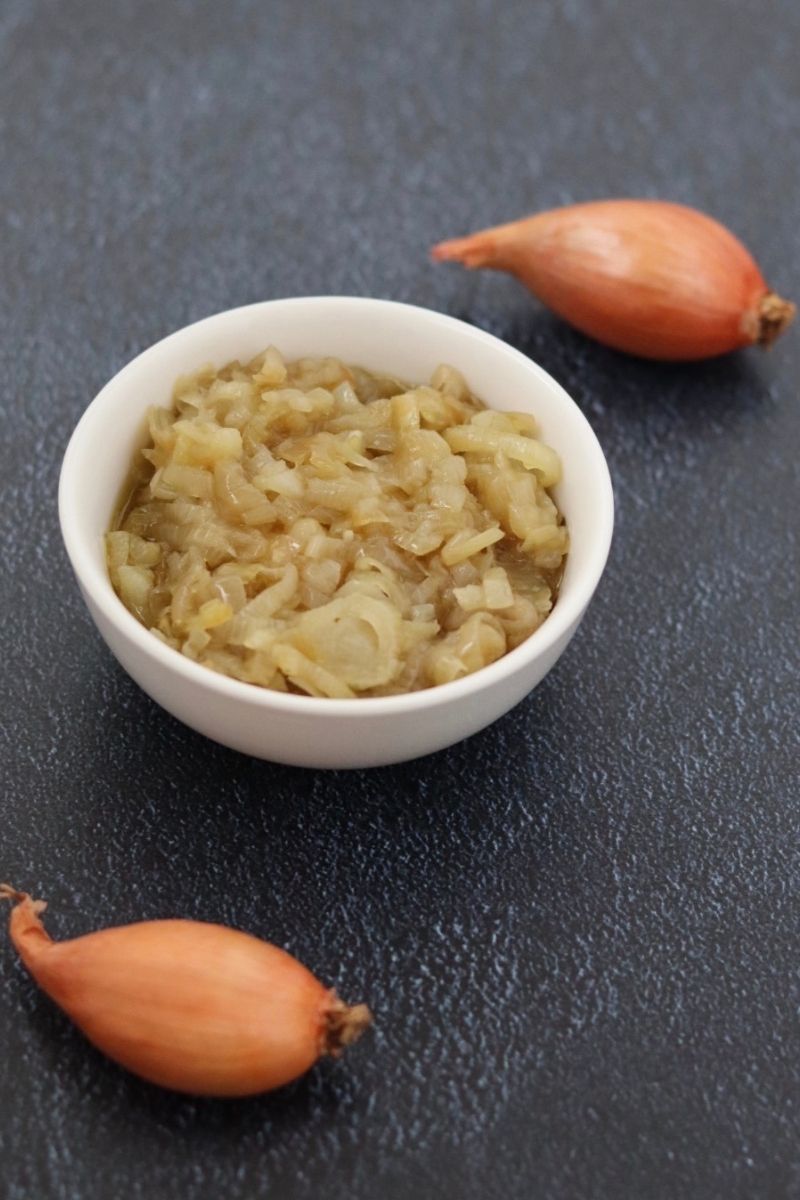 shallot sauce in a white bowl and 2 shallots next to it