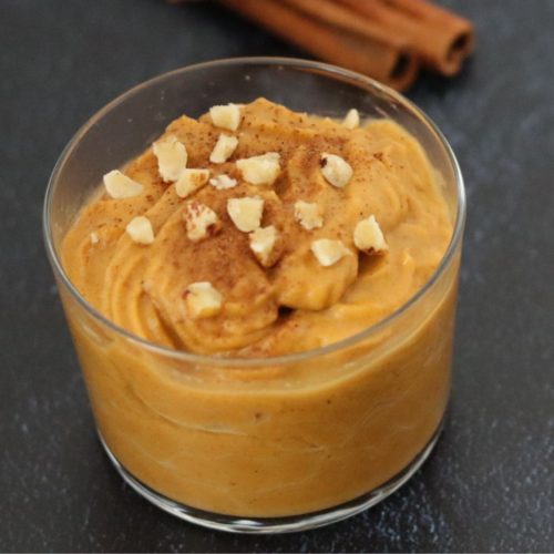 Pumpkin pudding in a small cup topped with pieces of peeled tigernuts and sprinkled with cinnamon