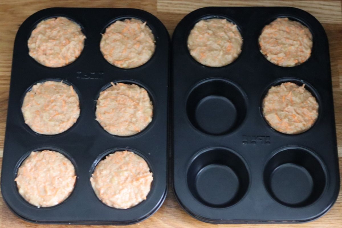 Banana carrot muffins batter in a muffin pan, 9 muffin cups are filled with batter.