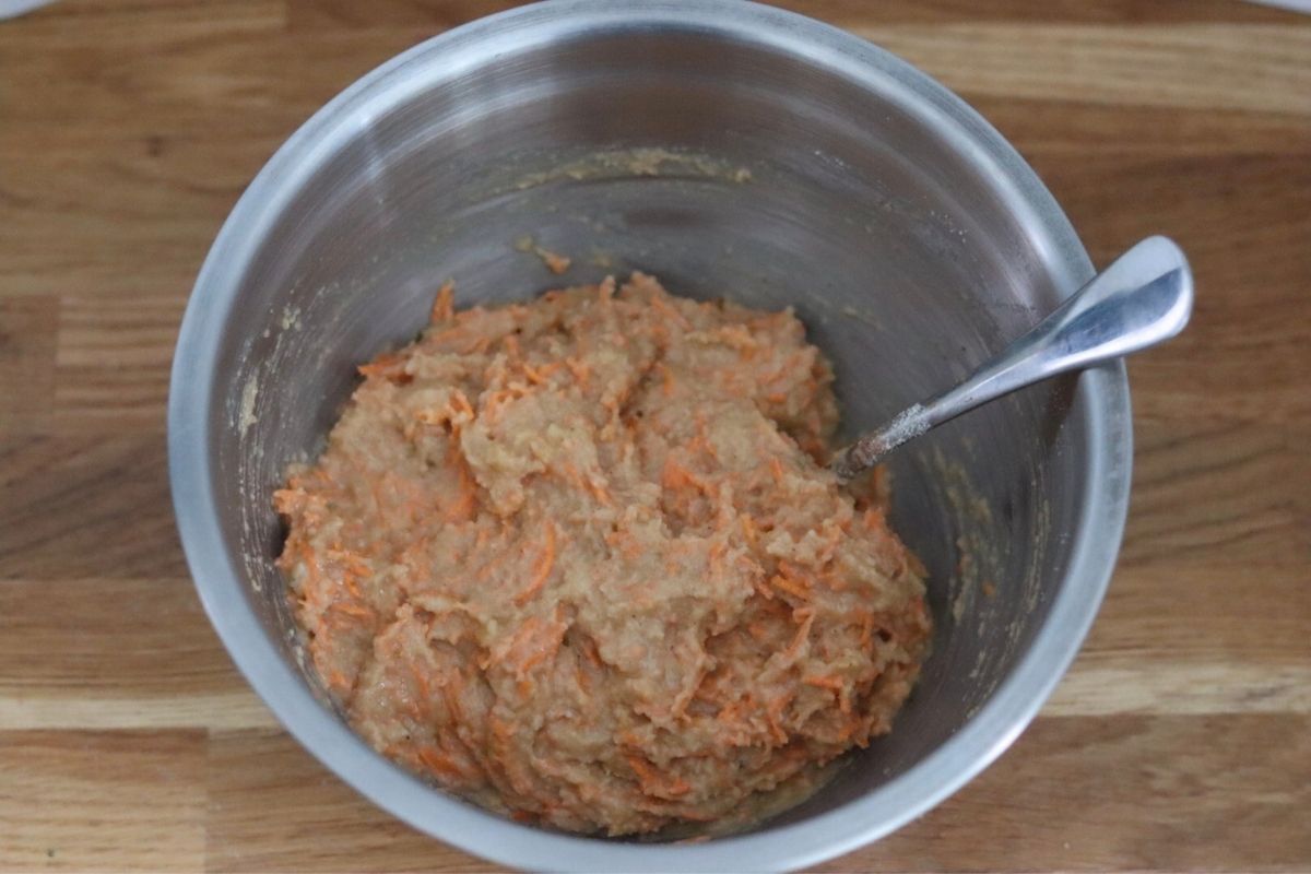 Banana carrot muffins batter in a large mixing bowl with a spoon.