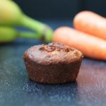 1 banana carrot muffin with bananas and carrots in the background