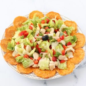 salade colorée avec patate douce, poulet, poivron rouge et poivron vert avec une olive noire au centre de l'assiette