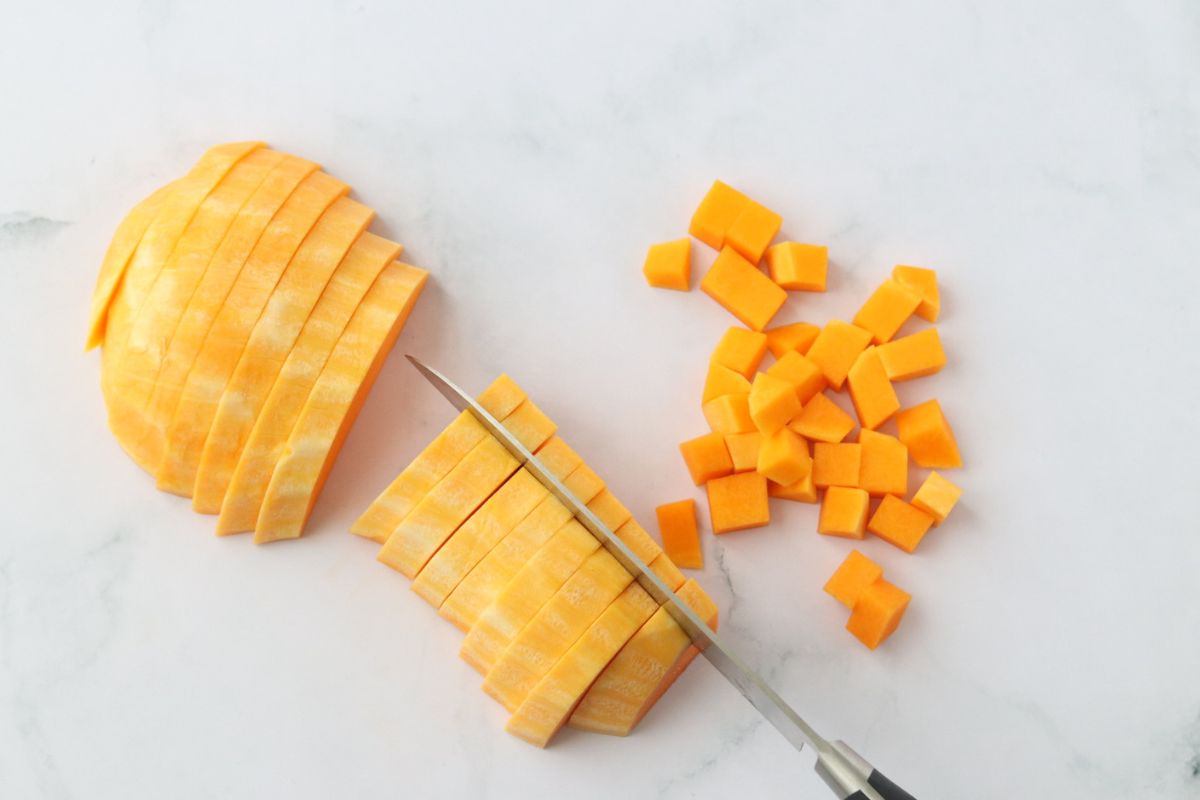 half a butternut squash being cut into cubes