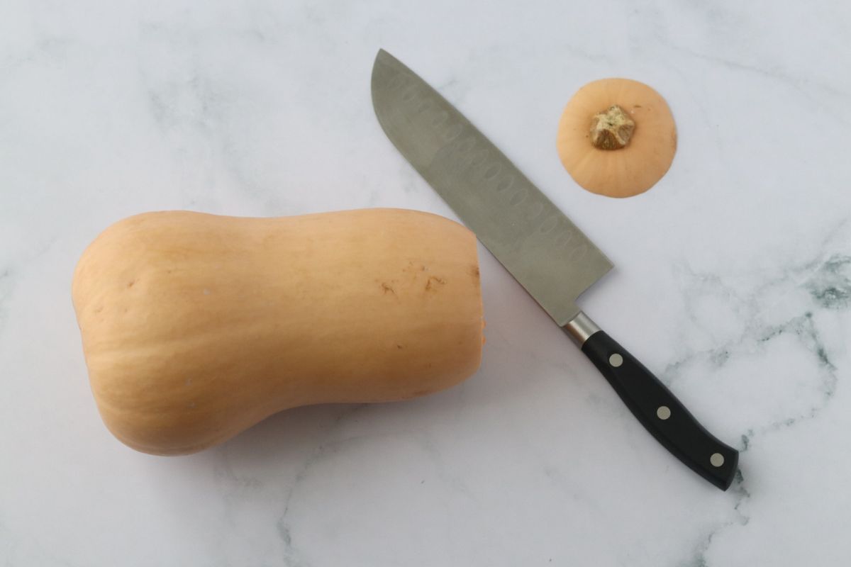 a butternut squash with the stem cut off and a large knife