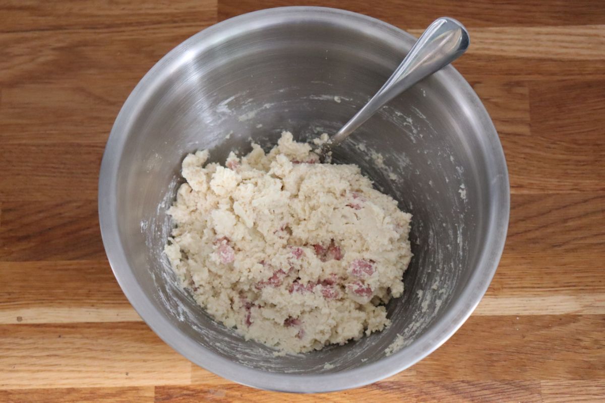 cheese and bacon roll dough in a mixing bowl with a spoon