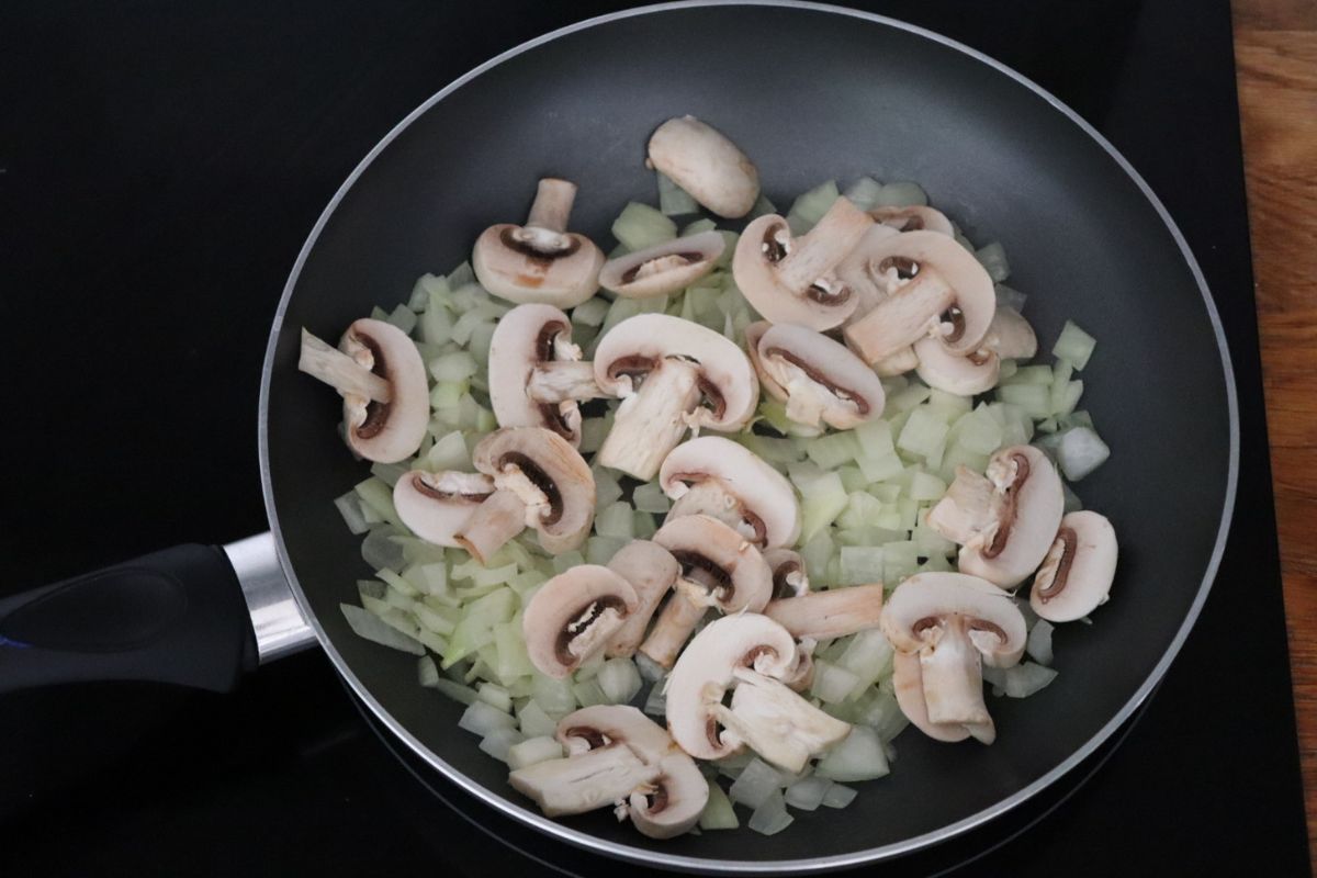 onions and mushrooms cooking in a frying pan