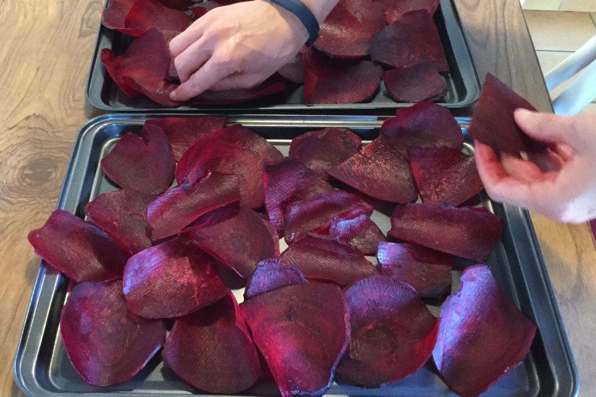 beet slices being spread in one layer on 2 baking trays