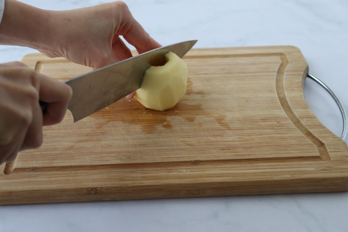 an apple being cut lengthwise in 2 with a chef knife