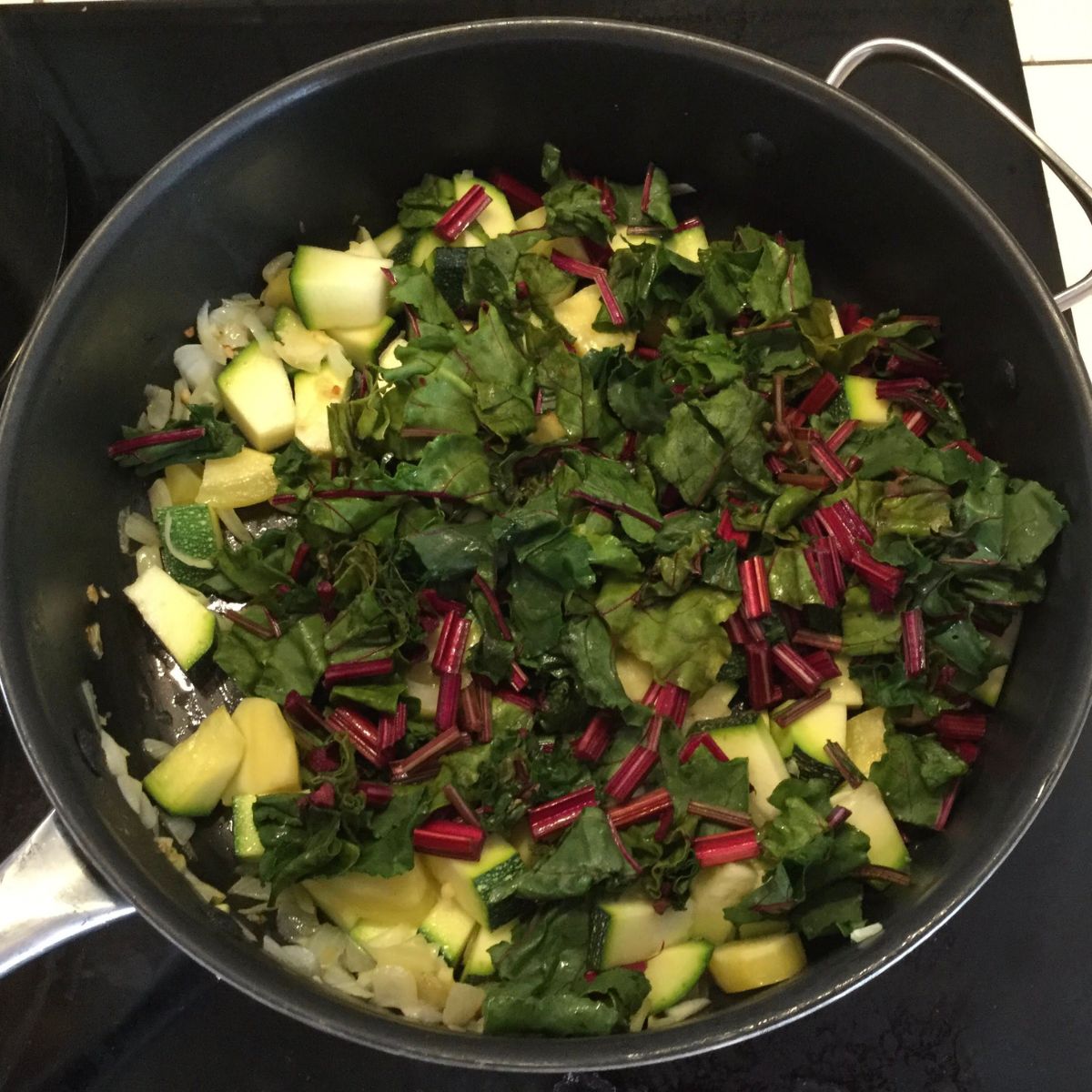 sauteed vegetables and beet greens in a frying pan