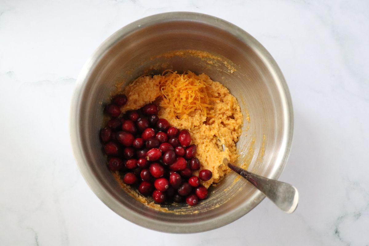 fresh cranberries and orange zest have been added to the bowl of muffin batter