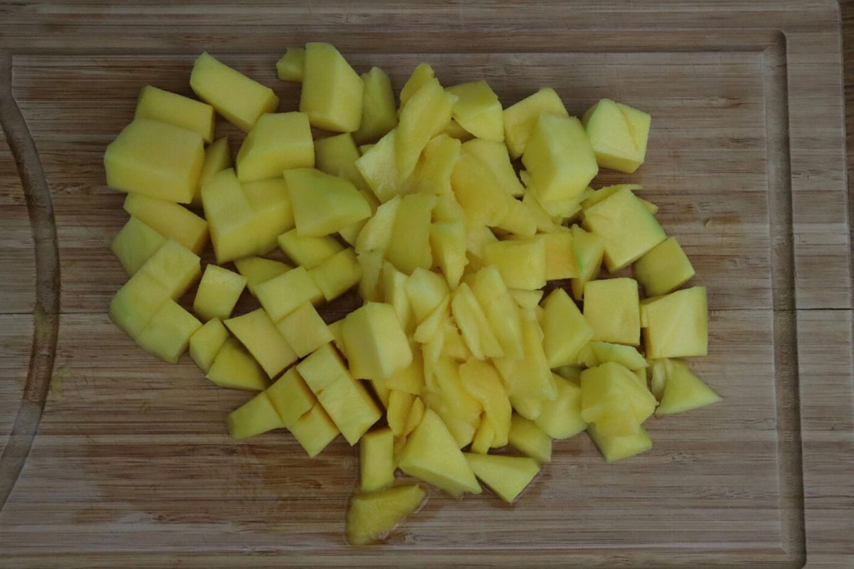 mango bite sized cubes on a wooden board.