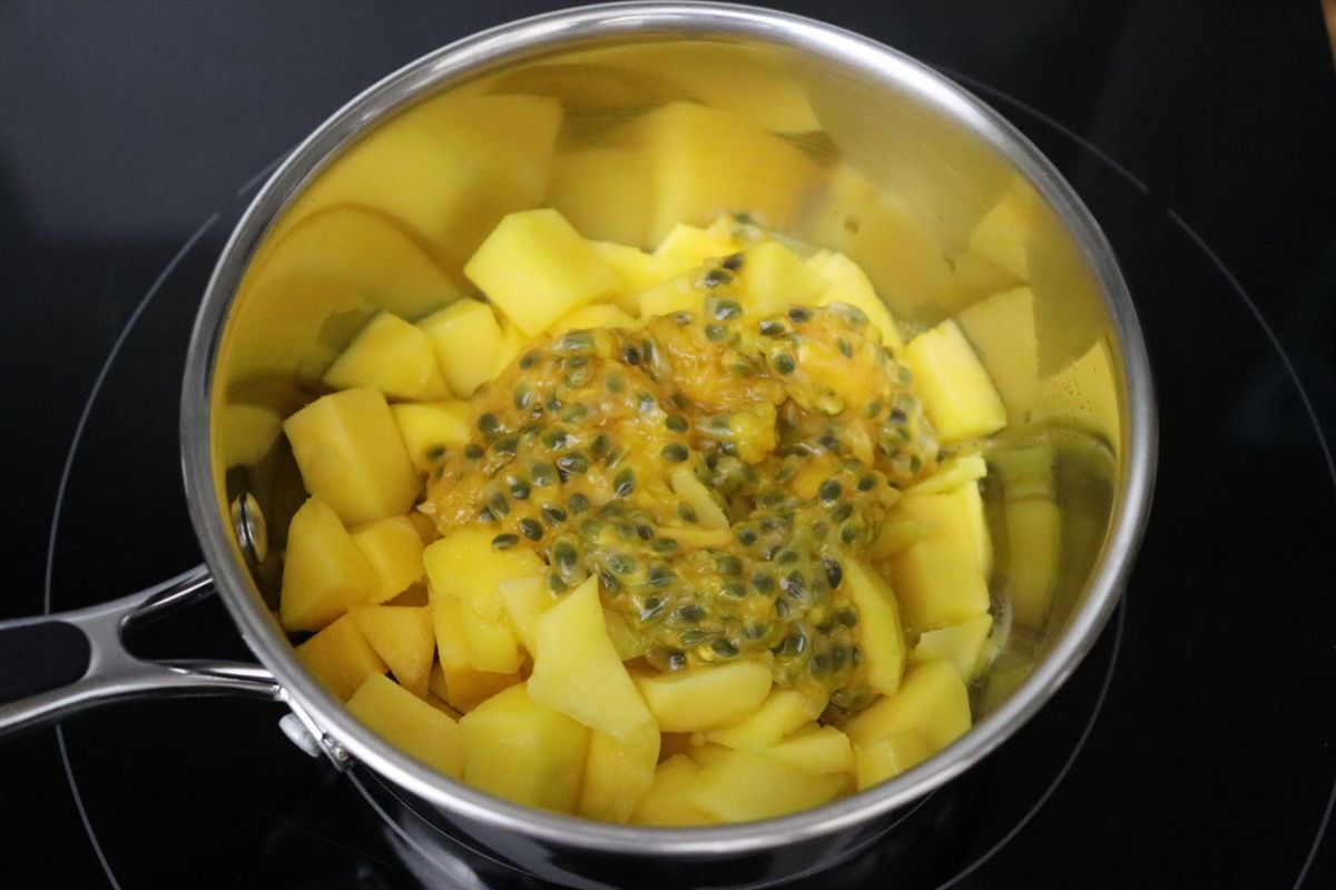 Des morceaux de mangue et de la pulpe de fruits de la passion dans une casserole.