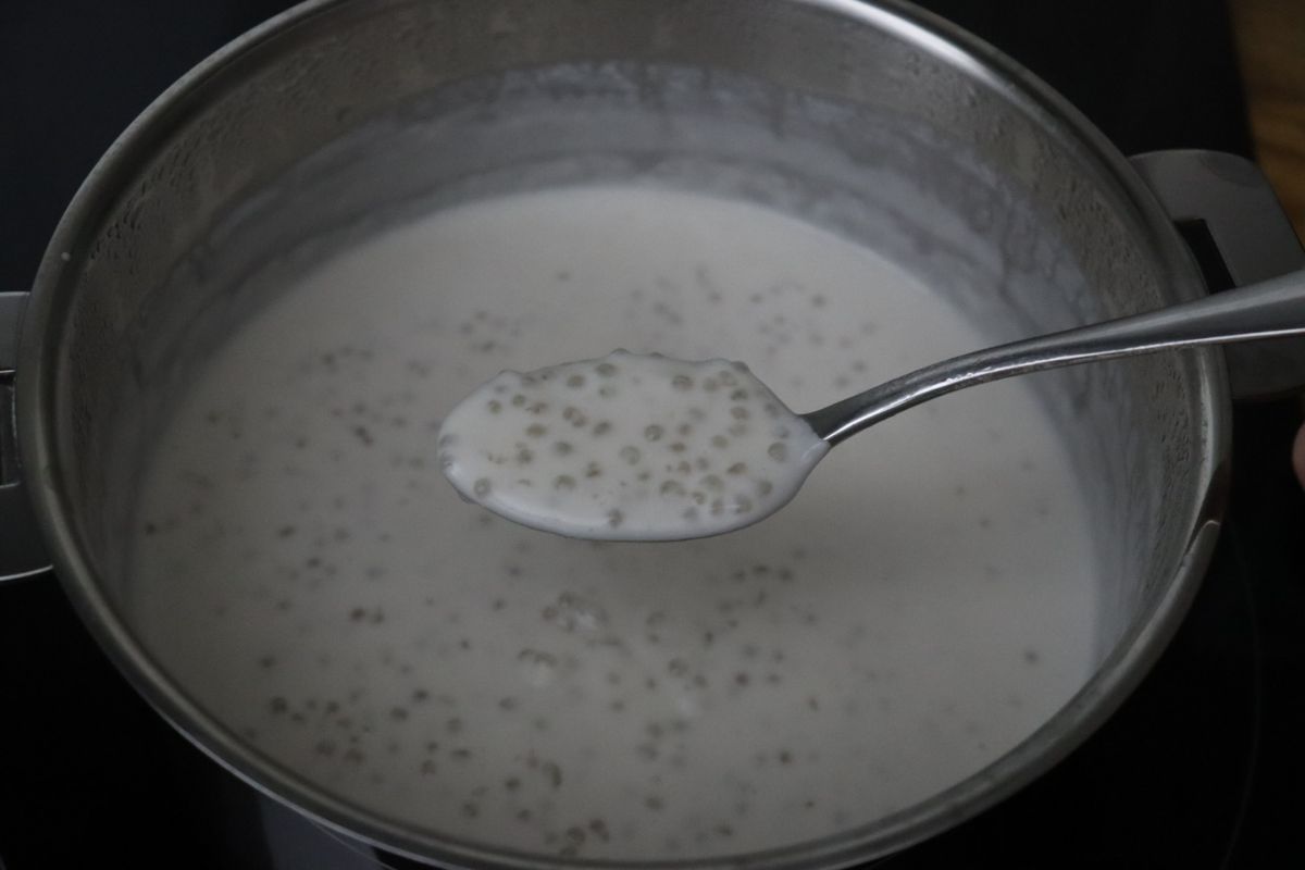 a spoonful of tapioca pudding being shown over the saucepan to show the creamy consistency.