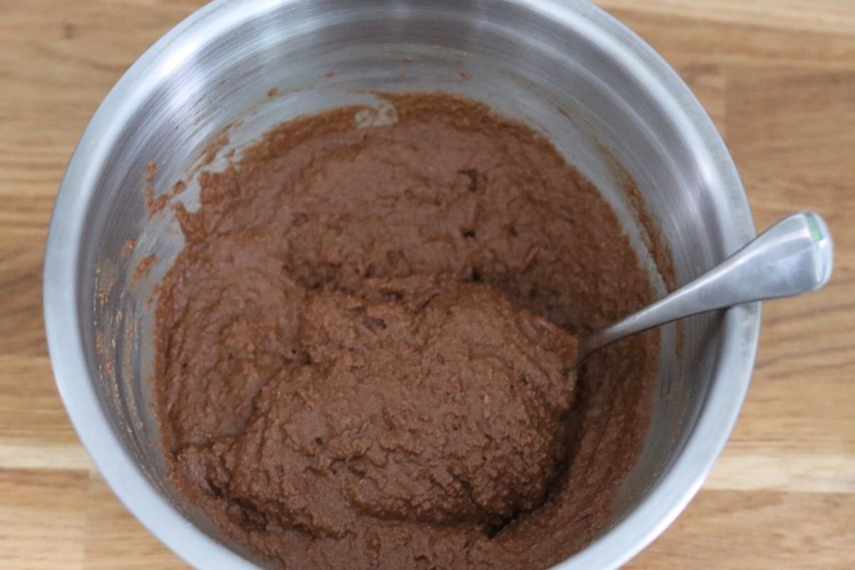 Chocolate zucchini bread batter in a large bowl with a spoon.