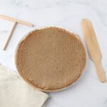 A pile of buckwheat crepes on a plate with wooden kitchen utensils on the side.