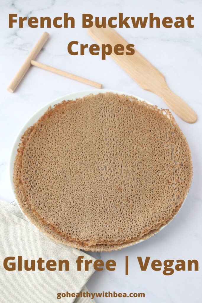 A pile of buckwheat crepes on a plate with wooden kitchen utensils on the side with a text overlay with the recipe title.