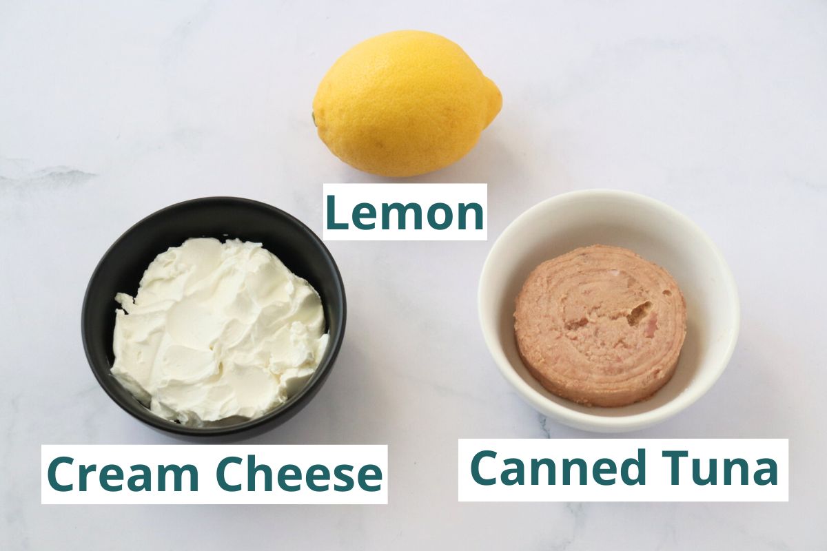 All the ingredients to make a tuna dip with cream cheese displayed on a kitchen counter: a lemon, some cream cheese and canned tuna. 