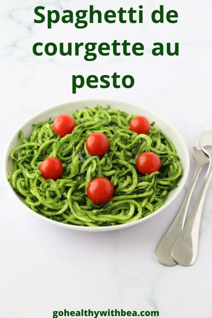 Une assiette remplie de spaghetti de courgette au pesto avec des tomates cerises parsemées dessus et le titre de la recette écrit en gros.