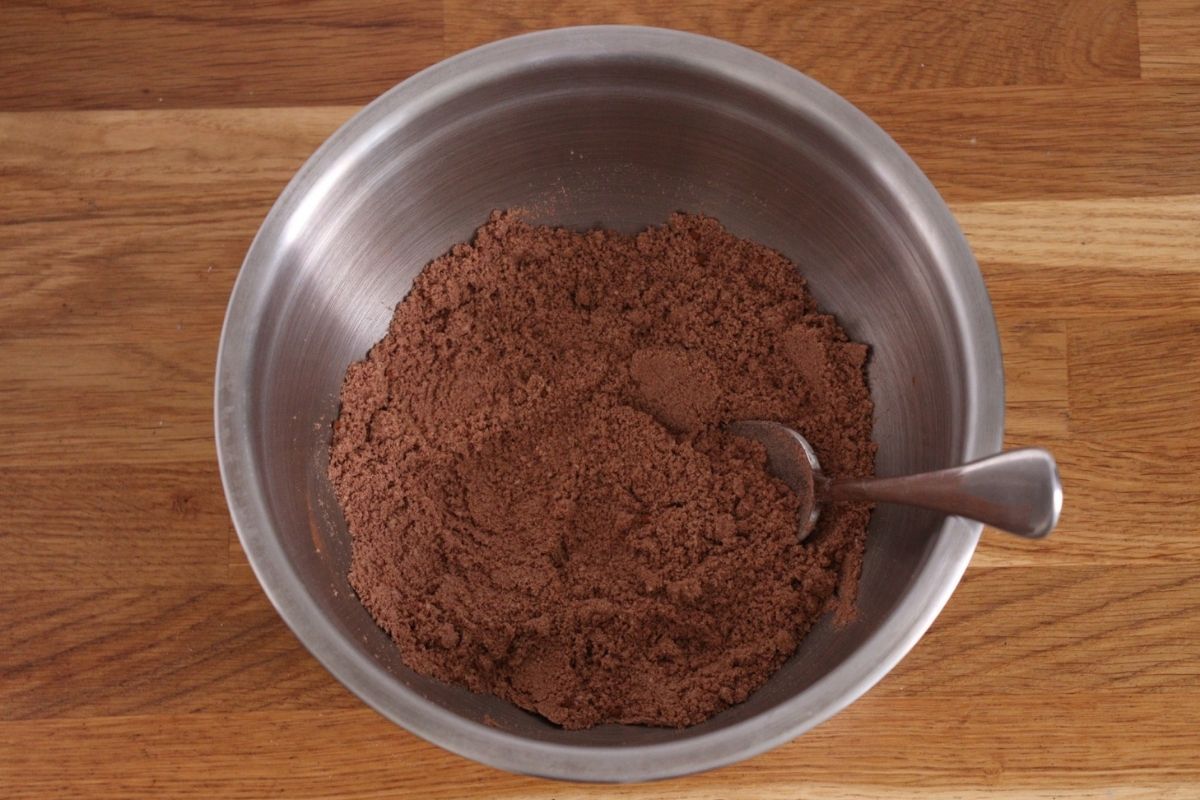 All the chocolate raspberry cake dry ingredients mixed together in a large bowl with a spoon.